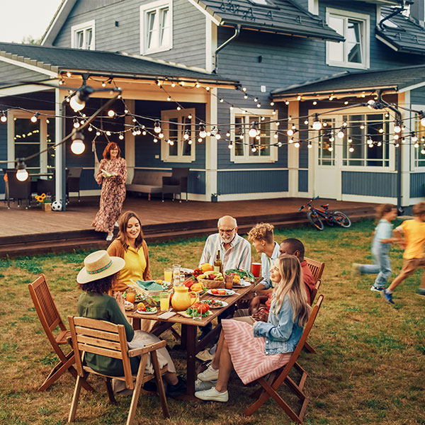 family in backyard eating a meal with string lights above