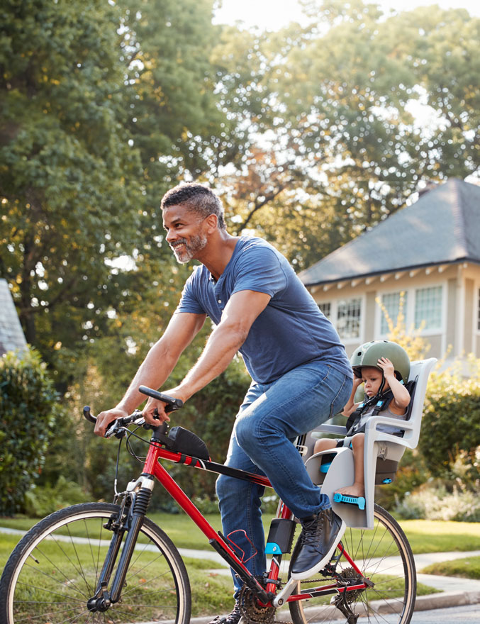 Father riding a bike with daughter in child seat