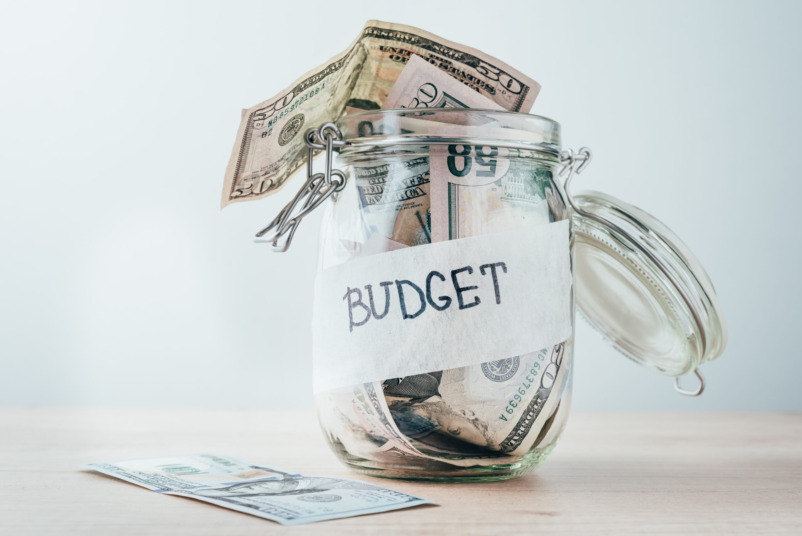 Glass jar filled with 50 dollar bills labeled "budget"