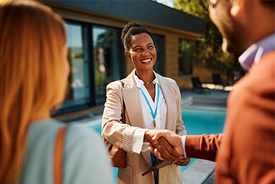 When is it time to hire a community management company? Happy African American community manager shaking hands with hoa board members.