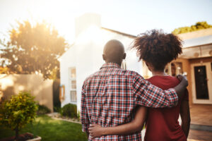 Rear view shot of a young couple admiring their new house outside.