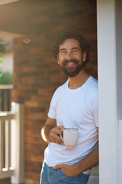 Happy man day dreaming while enjoying in cup of coffee on the porch. Copy space.