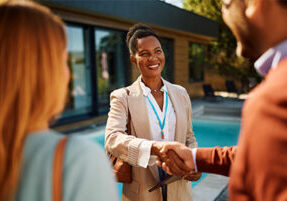 When is it time to hire a community management company? Happy African American community manager shaking hands with hoa board members.